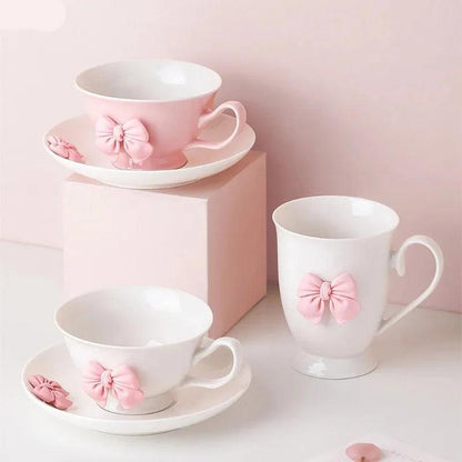 Porcelain tea cup and saucer set in white with pink bow detail, handle on right