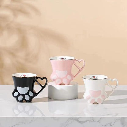 Set of cat paw mugs in black, pink, and white with heart handles and paw pad designs