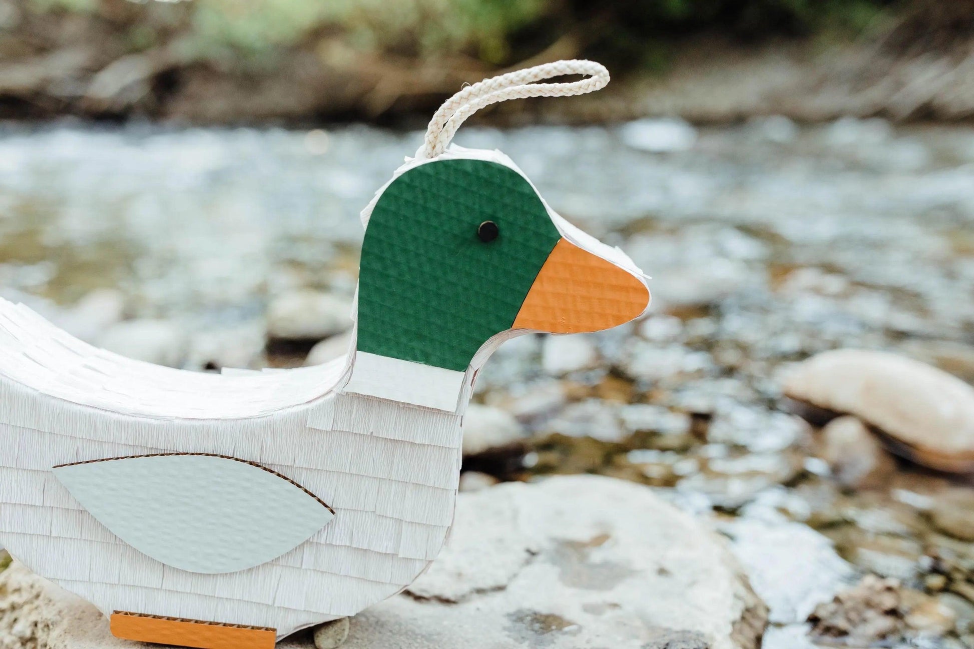 Duck piñata with green head and orange beak, white string handle