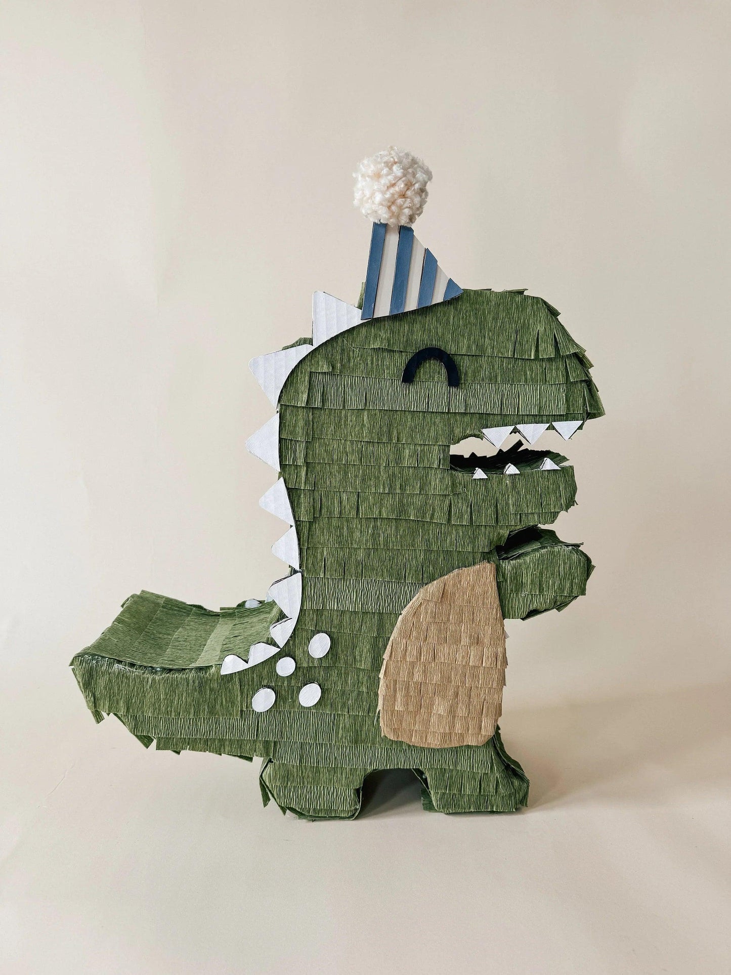 Handmade dinosaur piñata in green with beige belly and white teeth details