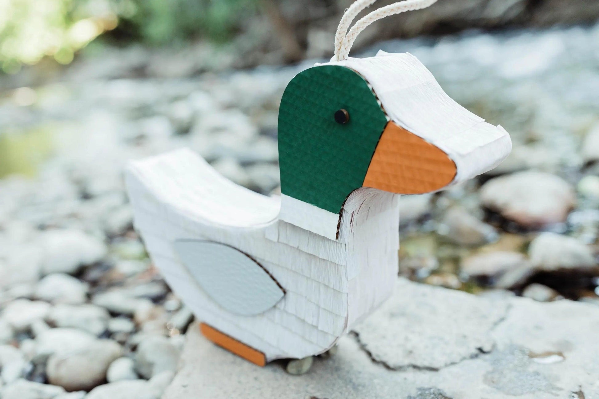Handmade duck piñata on wheels, white body with green head and orange beak