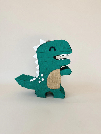 Teal dinosaur piñata with beige belly, black mouth, white teeth and dot eyes