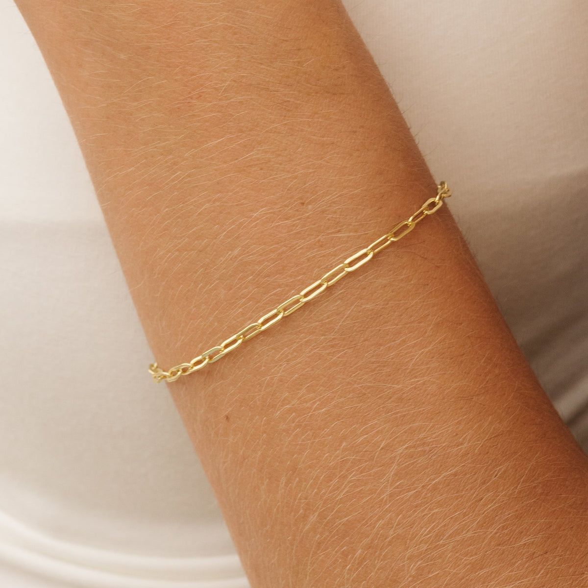 Gold paperclip link bracelet wrapped around wrist, slim chain style