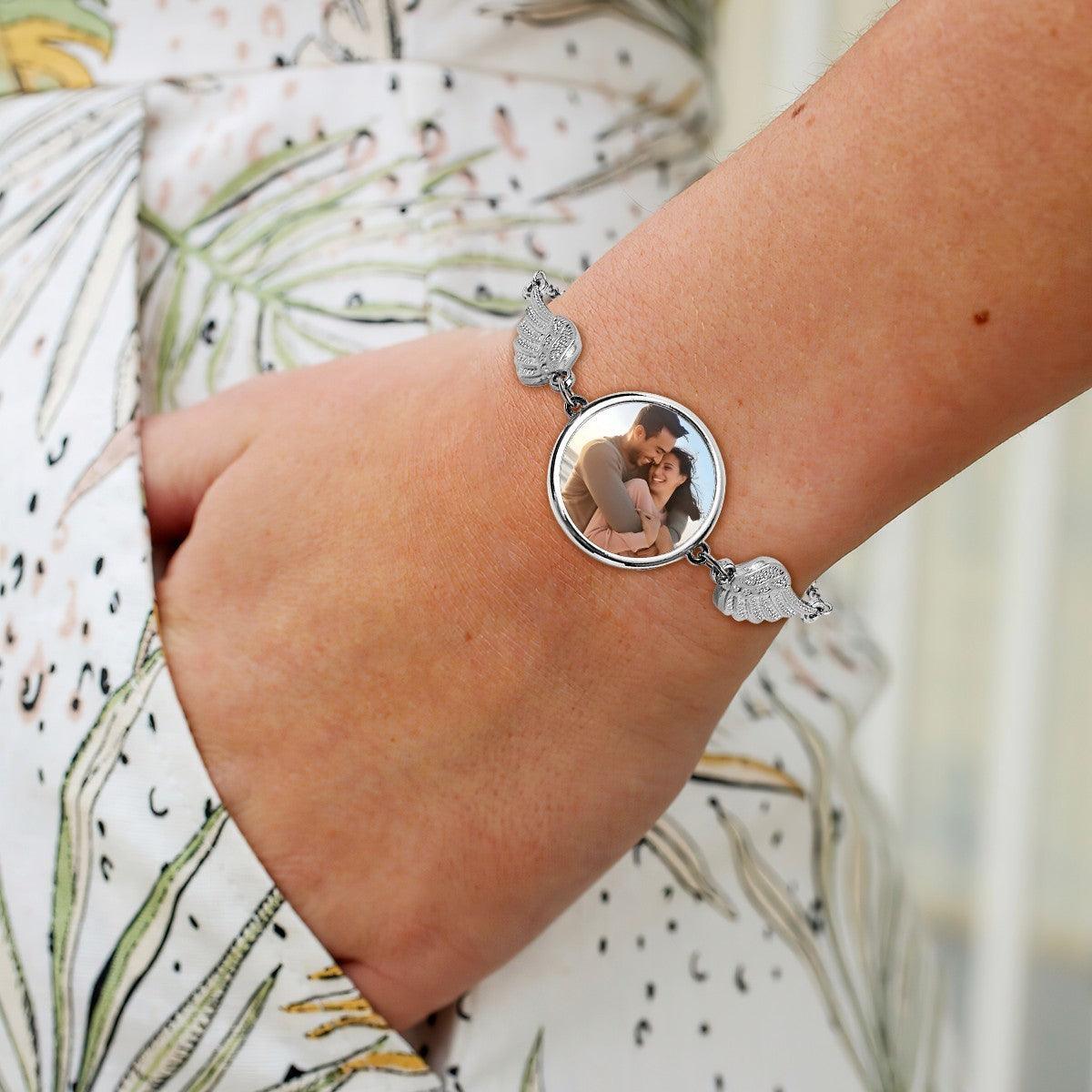 Silver angel wings photo charm bracelet with round locket on wrist