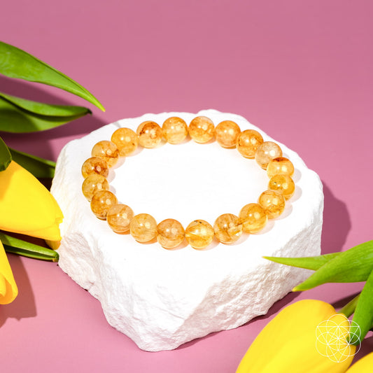 Golden healer quartz beaded bracelet with honey-gold round stones on white rock