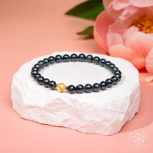 Beaded bracelet close-up with dark blue beads and a warm gold accent bead