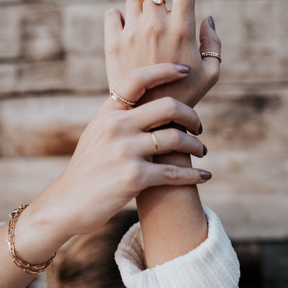 Gold-filled paperclip bracelet layered with another linked bracelet on the wrist.