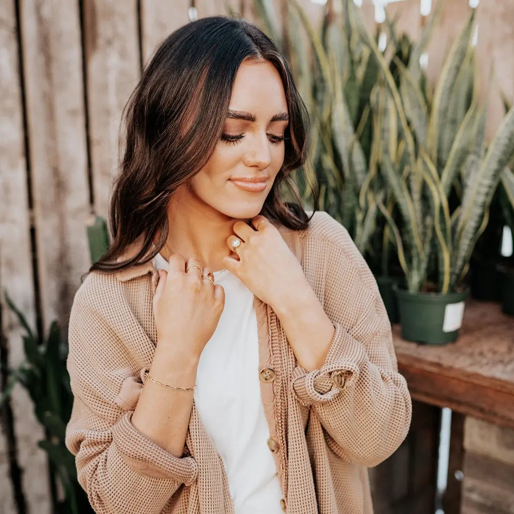 Gold-filled paperclip bracelet worn on the wrist with a knit cardigan.