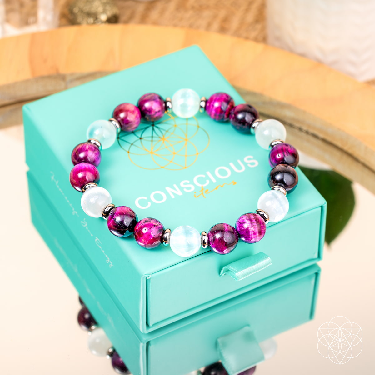 Beaded bracelet on a turquoise box with magenta-purple beads and white round stone beads.
