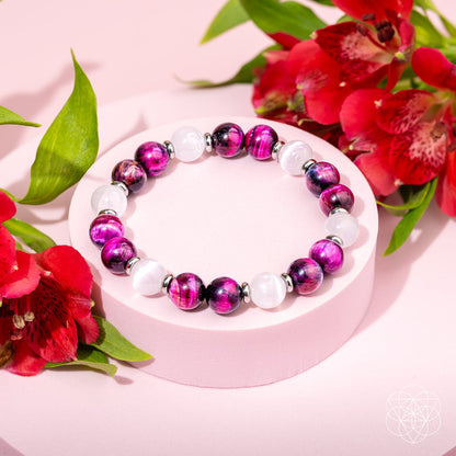 Beaded bracelet on a round display with magenta-purple tiger’s eye-style and white stones.