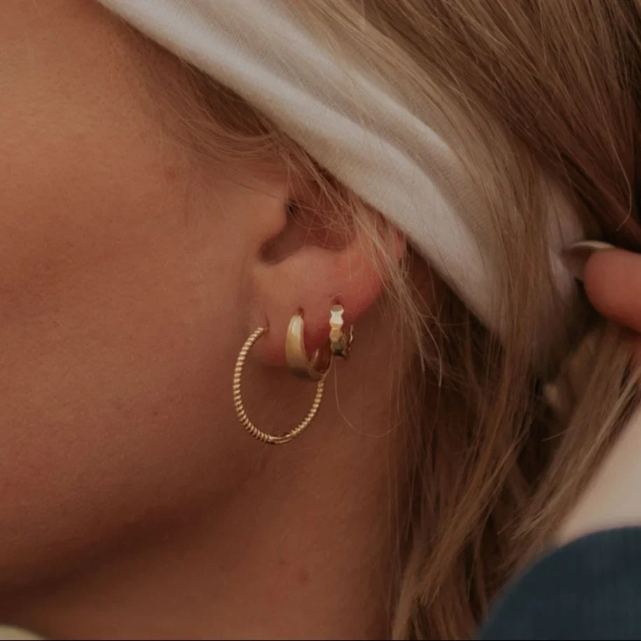 Gold chunky brushed huggie hoop worn with other gold hoops.