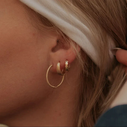 Gold chunky brushed huggie hoop worn with other gold hoops.