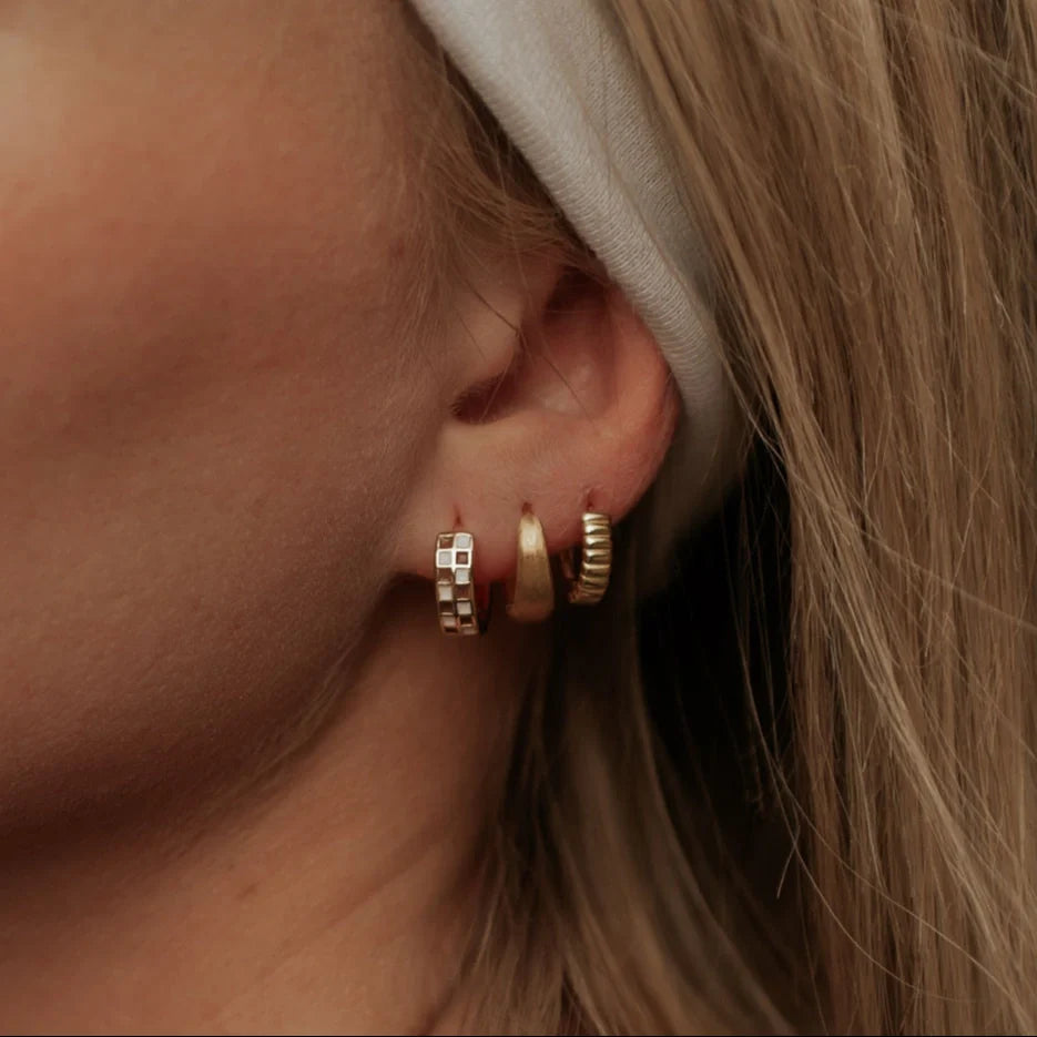 Gold ridged huggie hoop worn with two other hoops