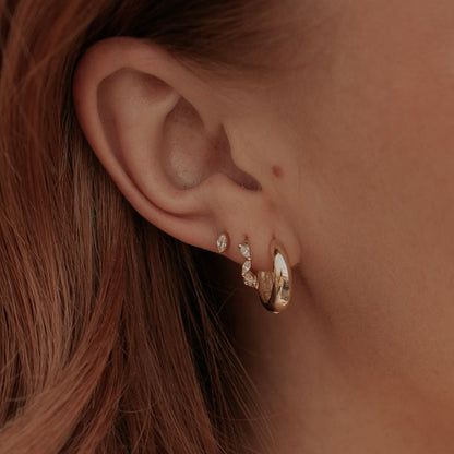 Gold diamond hoop earrings worn on an ear