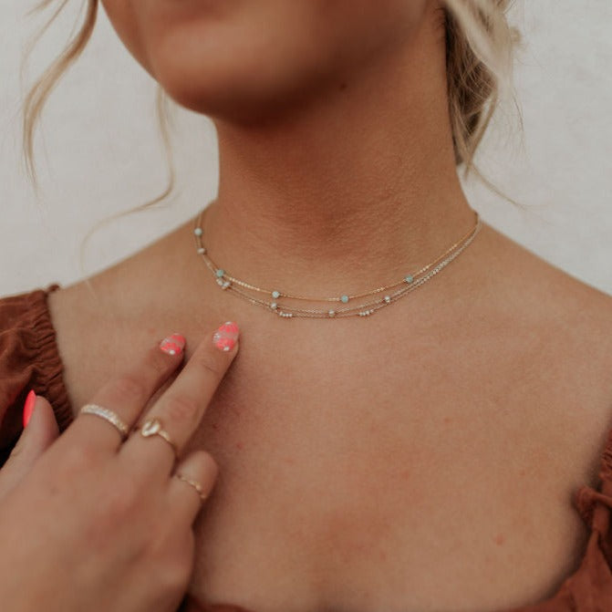 Three fine layered necklaces with small turquoise beads, worn at the neck