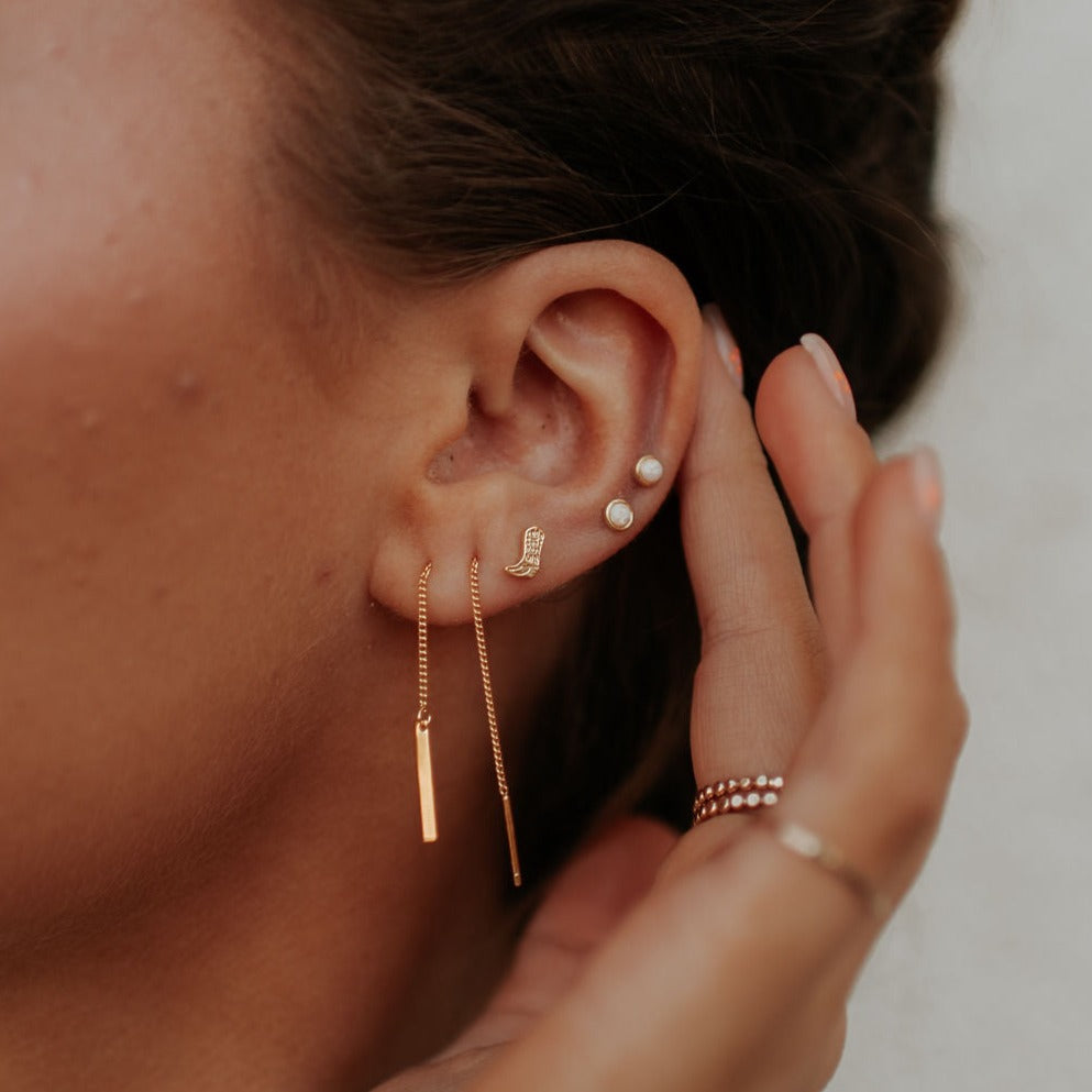 Round opal stud earring worn in an ear with other earrings