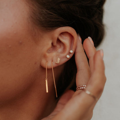Round opal stud earring worn in an ear with other earrings