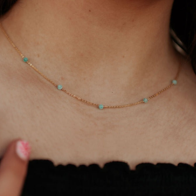 Close-up of a gold-tone chain with evenly spaced turquoise beads