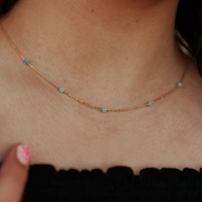 Close-up of a gold-tone chain with evenly spaced turquoise beads