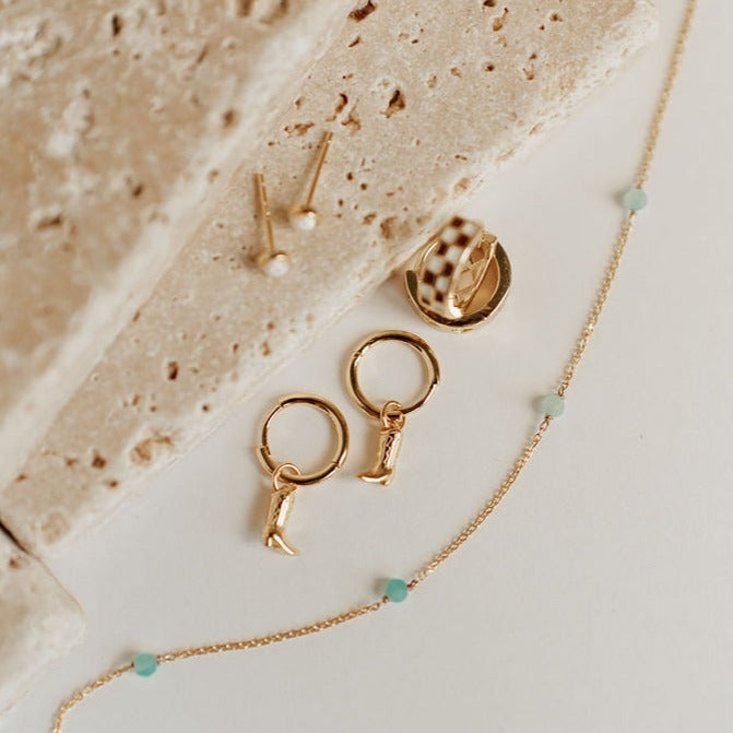Gold-tone necklace chain with turquoise beads beside gold-tone earrings