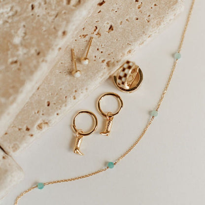 Gold-tone necklace chain with turquoise beads beside gold-tone earrings