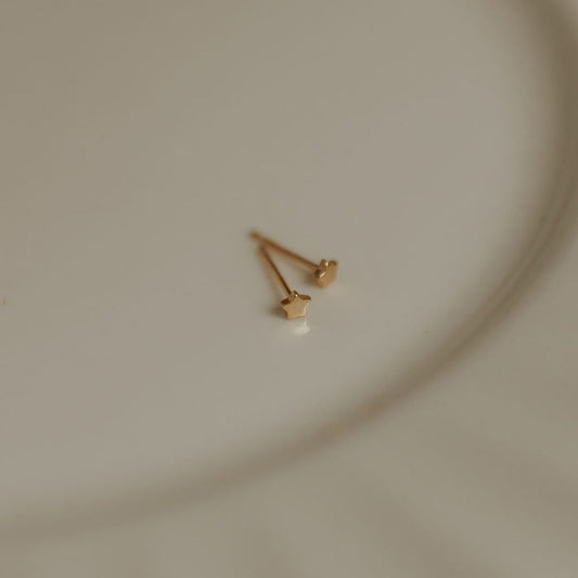 Mini gold star stud earrings shown from the back with posts visible