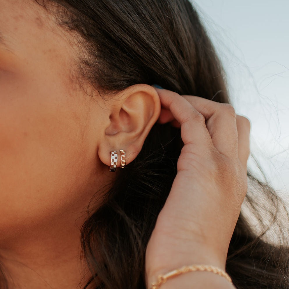 Gold Peri hoops worn on an ear, showing their linked texture.