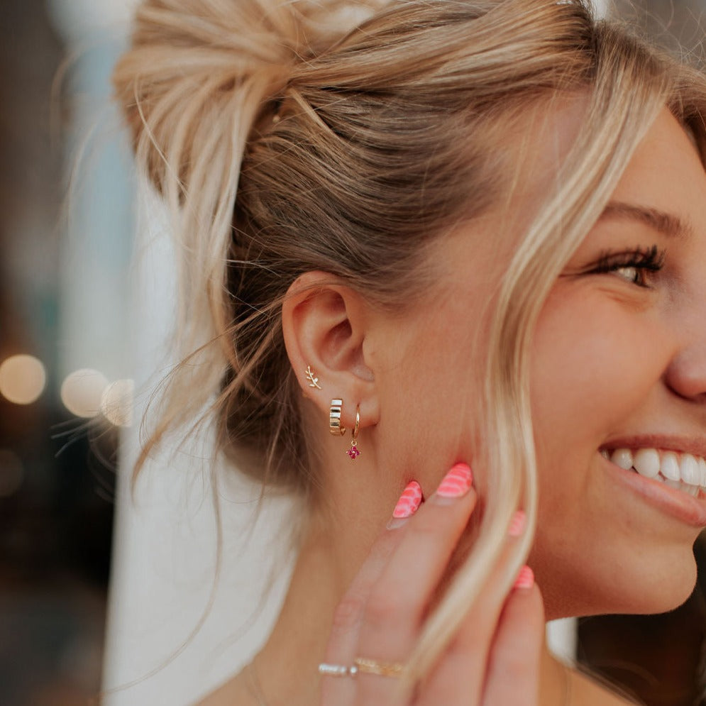 Gold Tate hoop earrings with ridged bands, worn with other earrings.