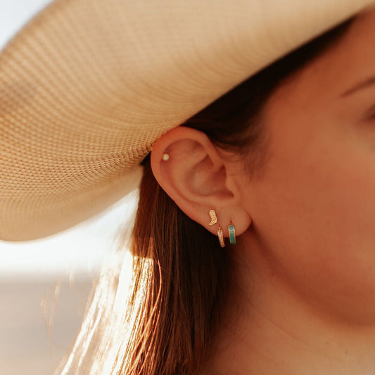 Gold-tone boot stud earring worn with other small earrings