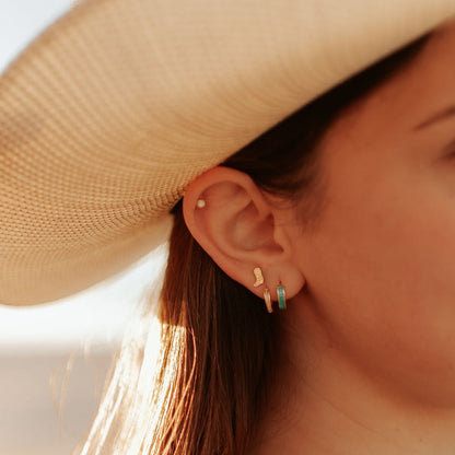 Gold-tone stud earrings with round opal stones, shown worn in an ear