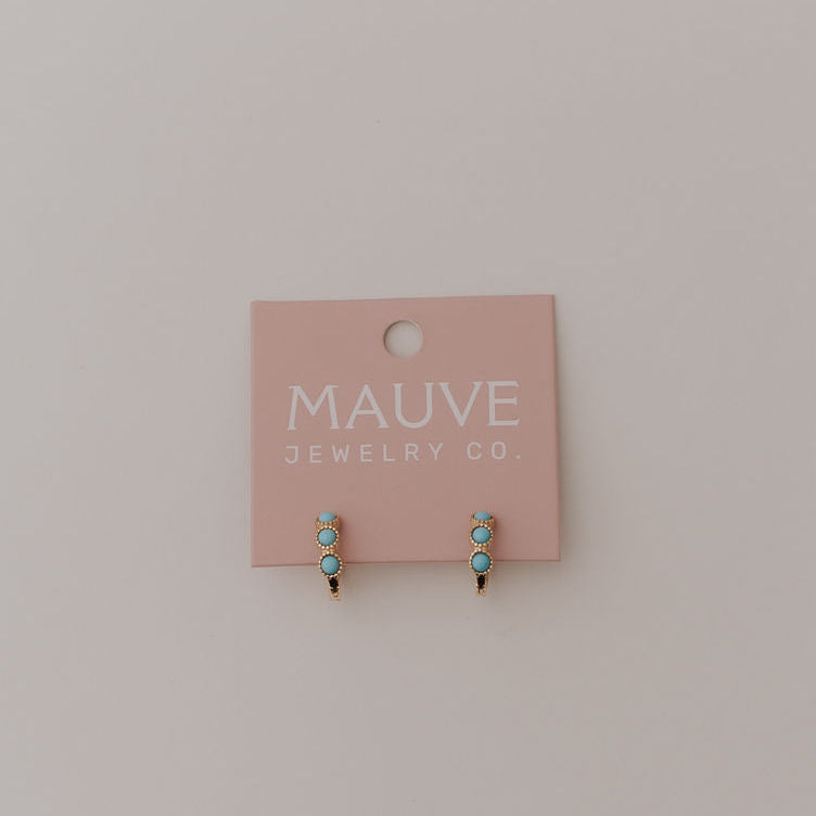 Gold turquoise huggie hoop earrings displayed on a jewelry card.