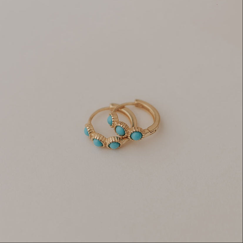 Gold huggie hoop earrings with turquoise stones and ridged detailing.