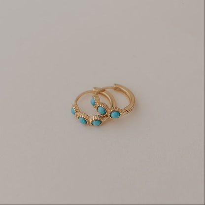 Gold huggie hoop earrings with turquoise stones and ridged detailing.