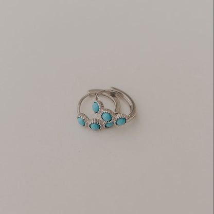 Silver turquoise huggie hoop earrings shown together from the front.