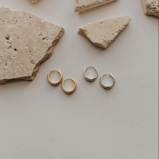 Gold and silver chunky brushed huggie hoops shown in pairs.