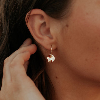 Gold vermeil hoop earring with a hammered disc charm, worn on the ear