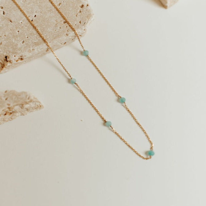 Fine gold-tone necklace with spaced turquoise beads, shown in a close-up