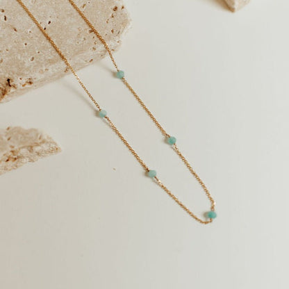 Fine gold-tone necklace with spaced turquoise beads, shown in a close-up