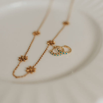 Gold-tone turquoise hoops beside a floral chain necklace