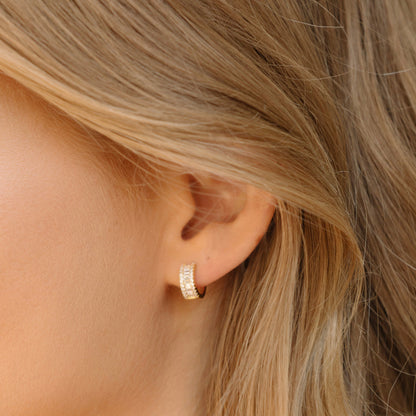 Gold-tone baguette hoop earring on ear, side view with clear stone rows