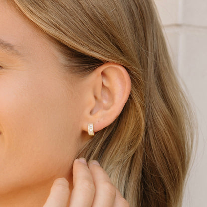 Small gold-tone baguette hoop earrings worn, showing stacked stone rows