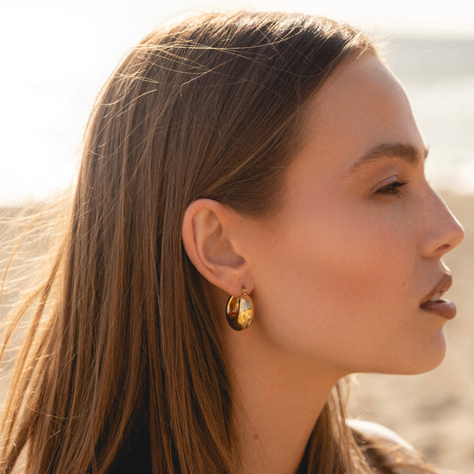 Gold-tone bubble hoop earring on model’s ear, curved teardrop loop