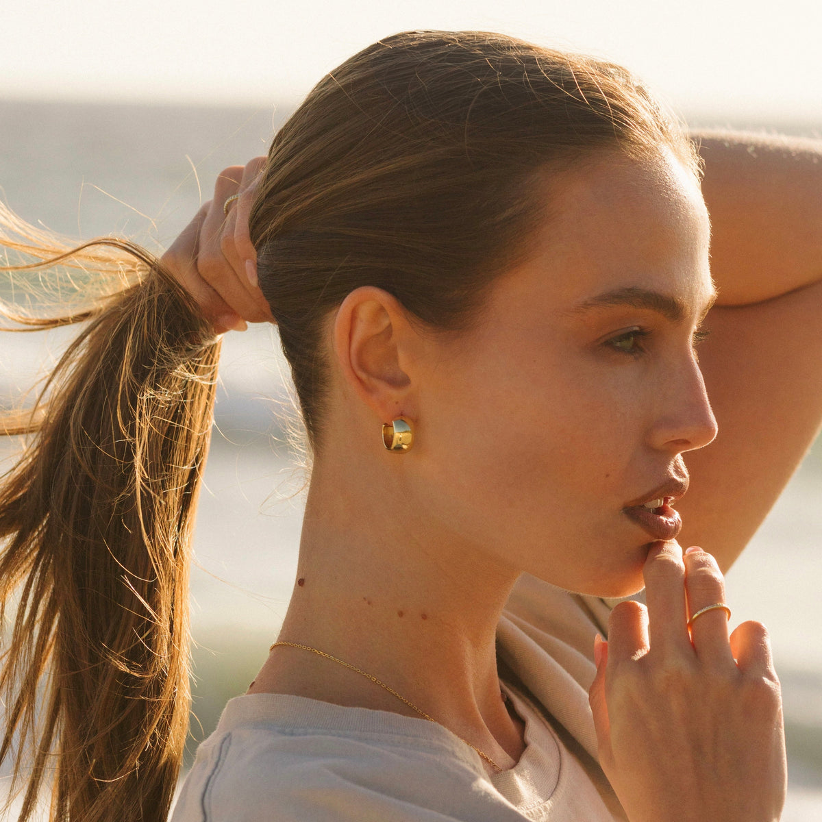 Gold dome hoop earrings on side profile, polished curved hoops
