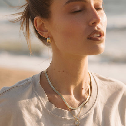 Gold dome hoop earrings with polished curved dome on ear