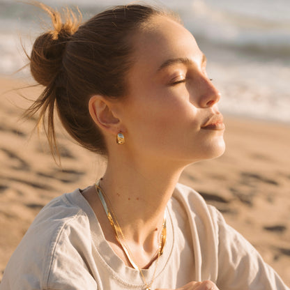 Gold dome hoop earrings on ear, small rounded dome hoops