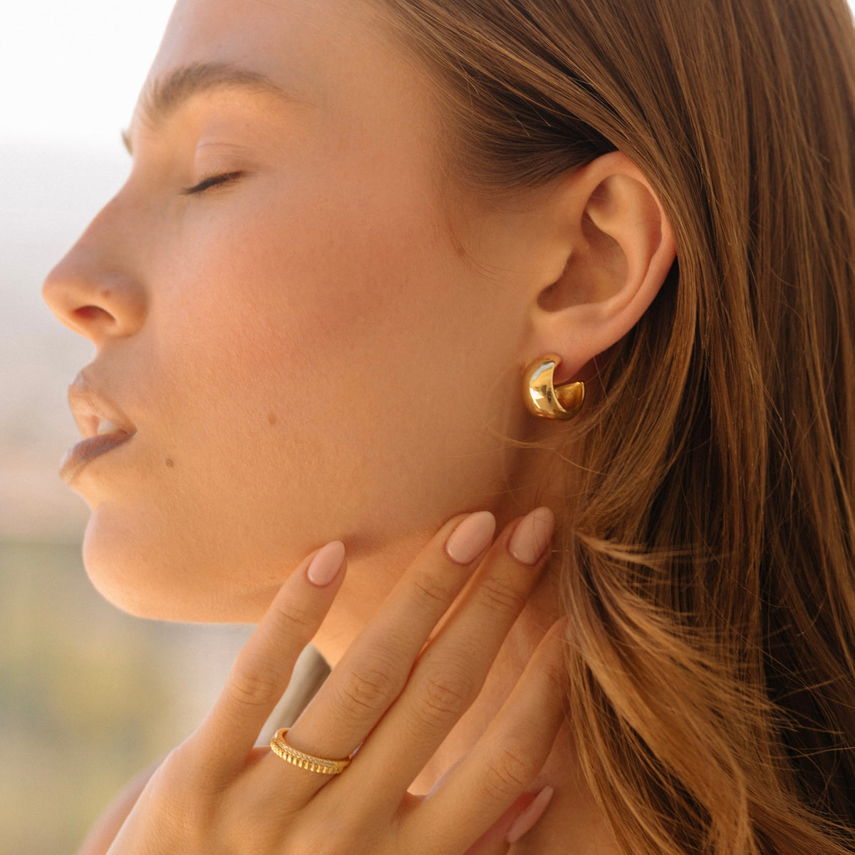 Gold dome hoop earrings on side profile, rounded dome design