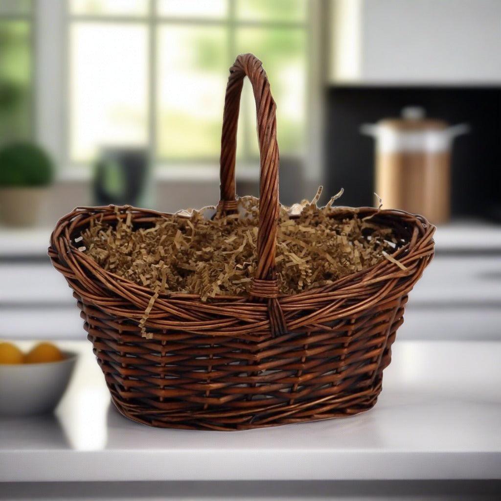 Wicker gift basket with tall loop handle and brown filler shreds
