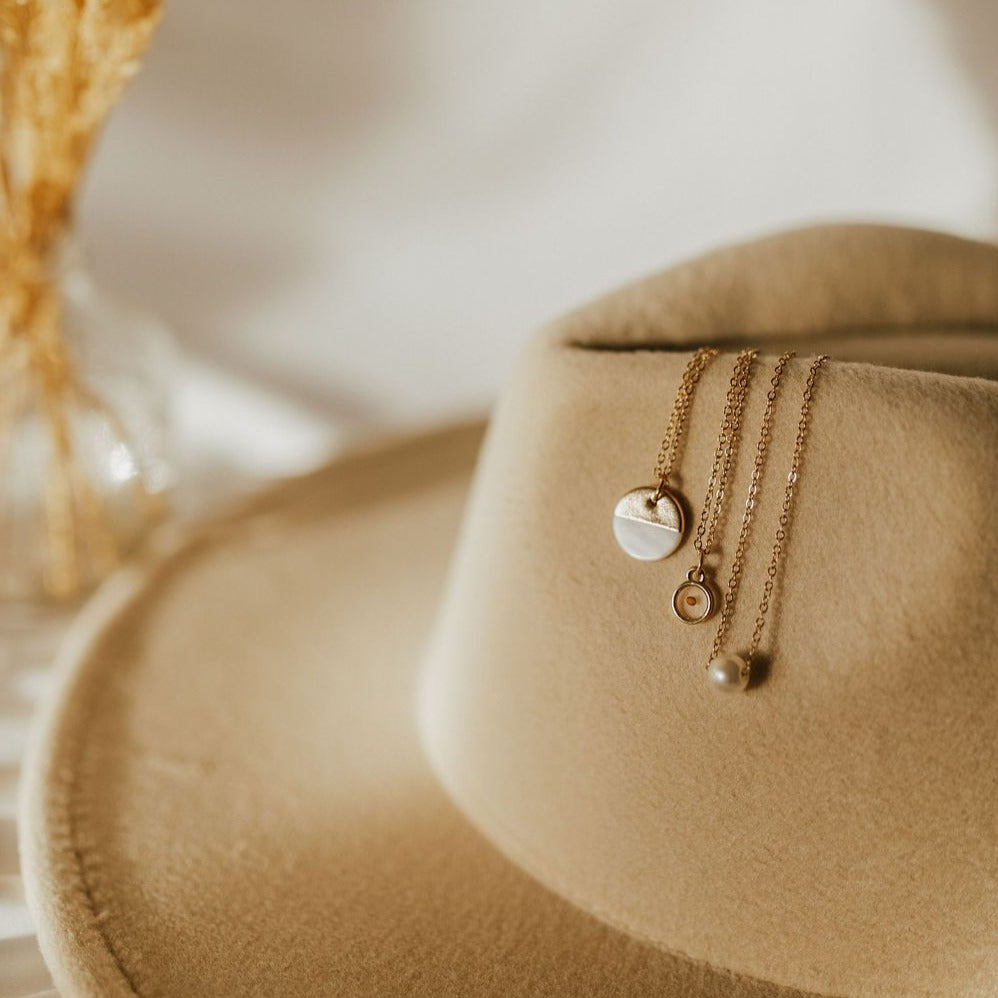Gold necklace with a small round mustard seed pendant