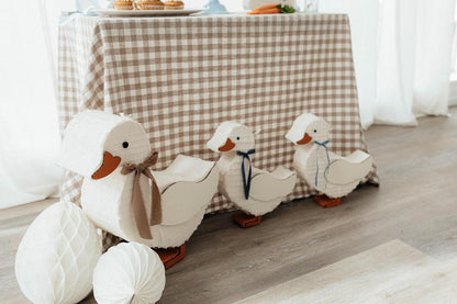 Group of duck piñatas: white ducks with brown beaks and navy bows on bases