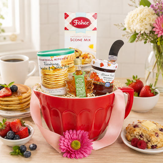 Red ceramic mug gift basket with baking mix, syrup, and assorted breakfast items